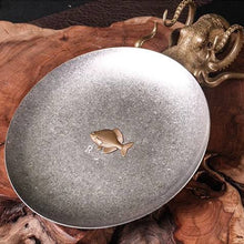 Load image into Gallery viewer, Rhodeus Plate resting on a wooden slab, angled view of the antiqued steel finish