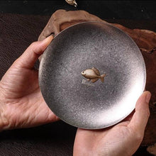 Load image into Gallery viewer, Rhodeus Plate held in two hands, showing the textured steel surface and brass bitterling